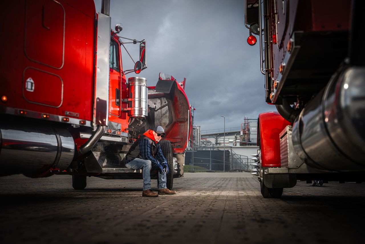 Two truck drivers taking a break beside red trucks